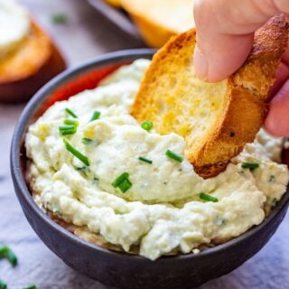 Scooping artichoke parmesan dip with crostini