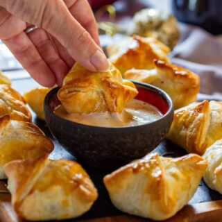 Dipping beef wellington bites to the sauce