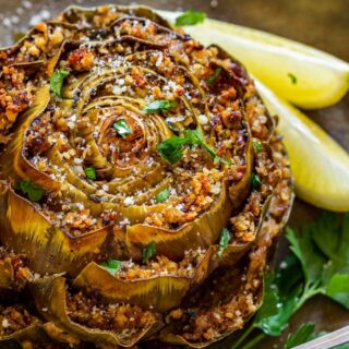 Stuffed artichoke on the plate with slices of lemon