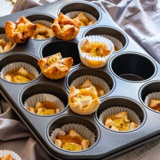 Freshly baked puff pasty brie bites on a muffin tray.