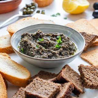 Homemade olive tapenade with breads and black olives.