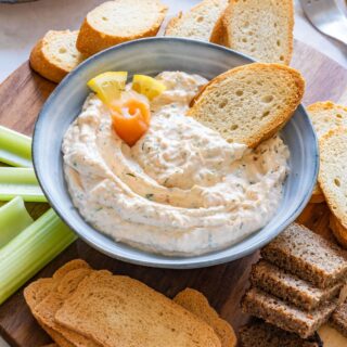 Bowl of homemade smoked salmon dip with lemon and toasted bread slices.