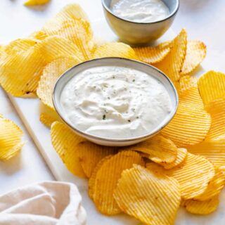 Small bowl of homemade chip dip surrounded with potato chips.