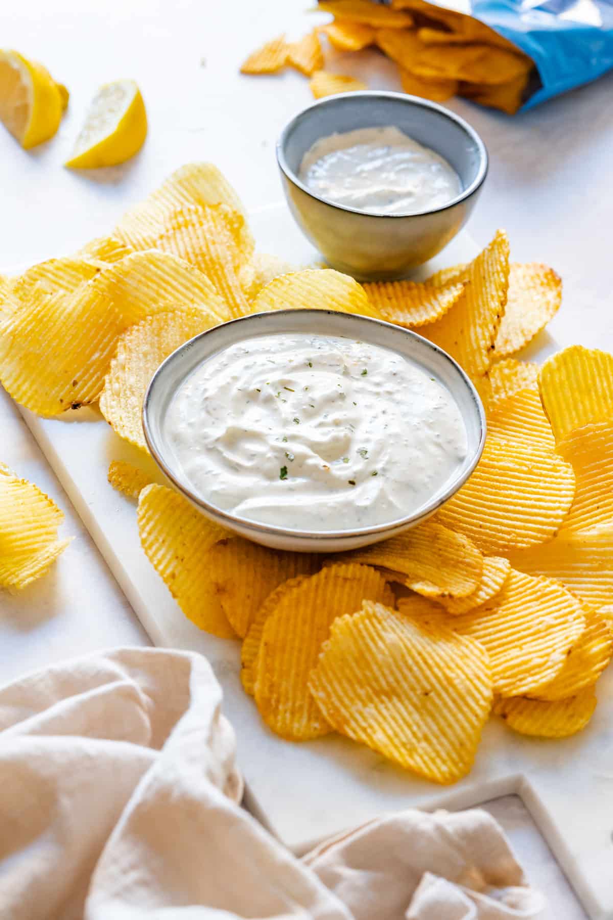 Small bowl of homemade chip dip surrounded with potato chips.