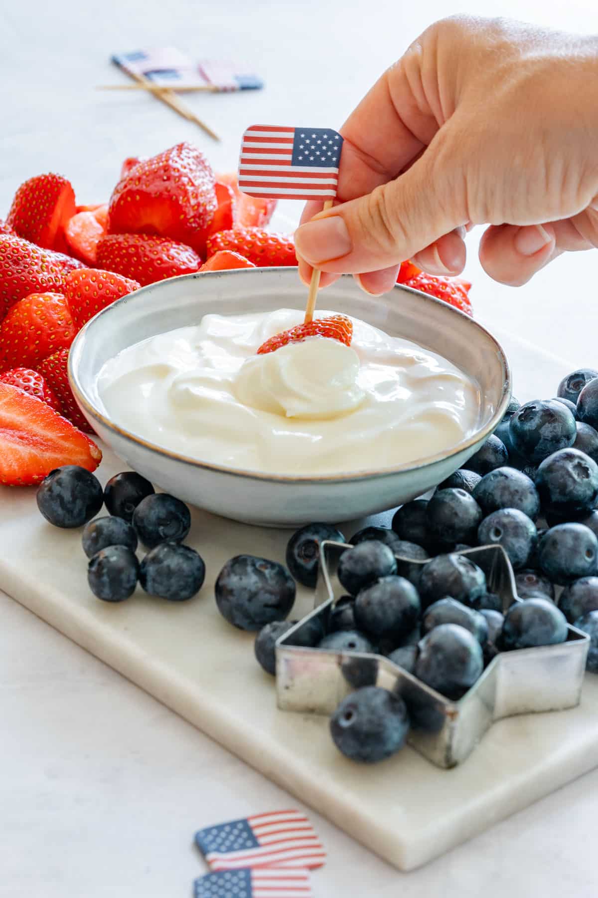 Hand scooping with strawberry homemade fruit dip.