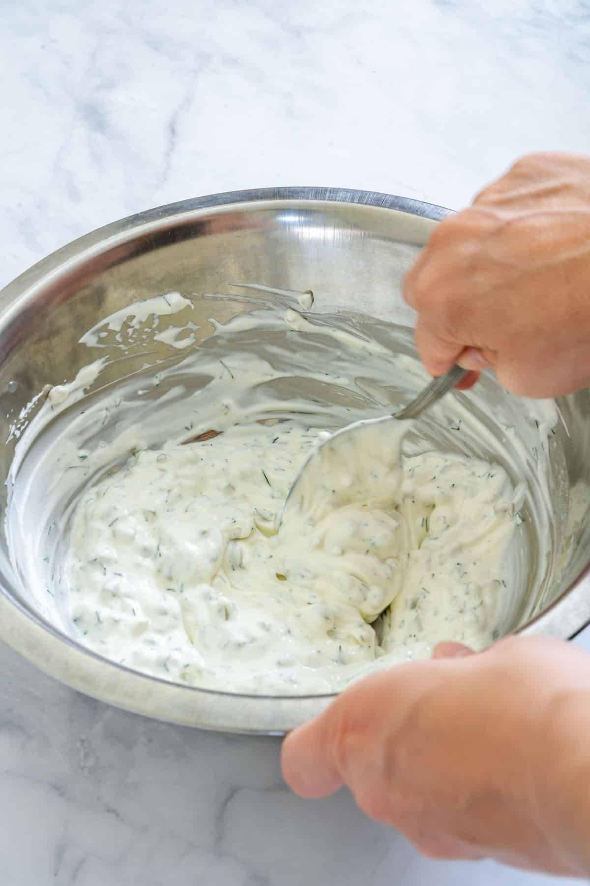 Mixing homemade dill pickle dip in a bowl.