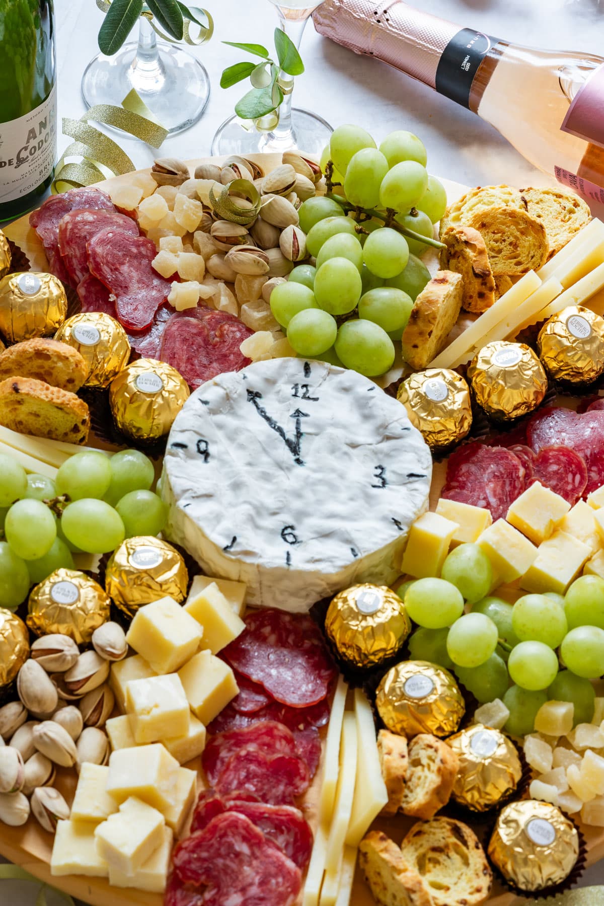 New Year's Eve charcuterie board with grapes, salami, nuts, chocolates and cheese clock.