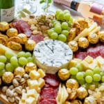 Cheese platter with grapes, salami, chocolates, nuts and wine. Cheese shaped like a clock.