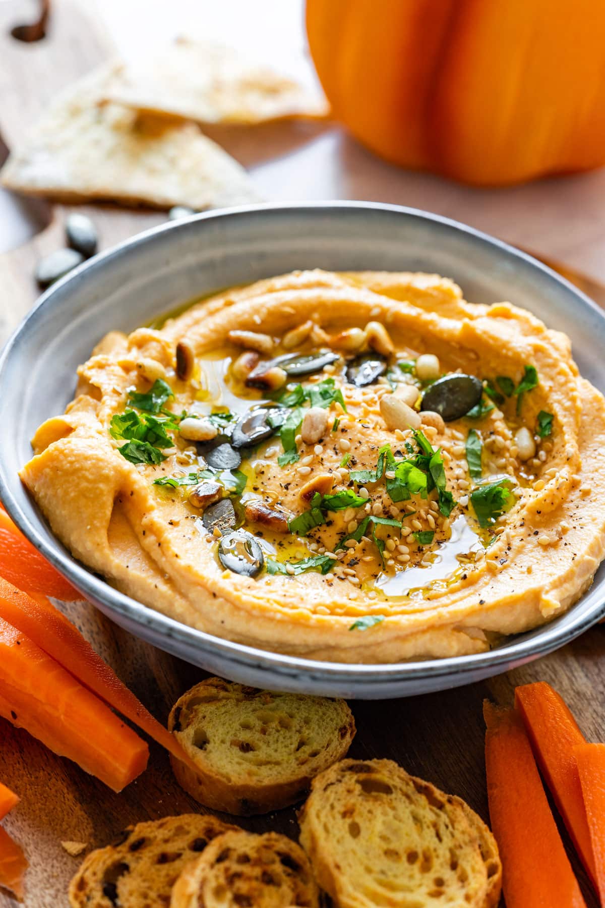 Homemade pumpkin hummus topped with green pumpkin seeds and herbs.