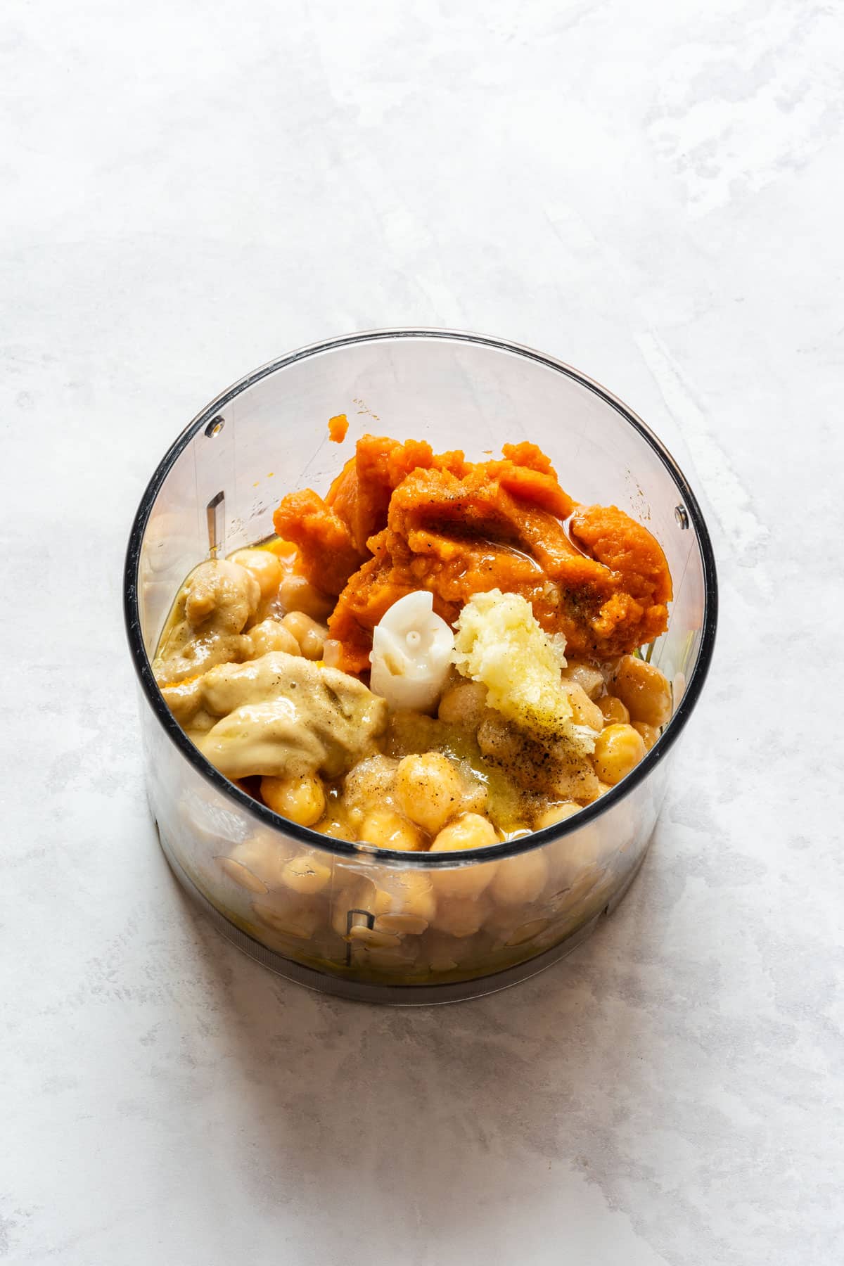 Pumpkin hummus ingredients in a food processor.