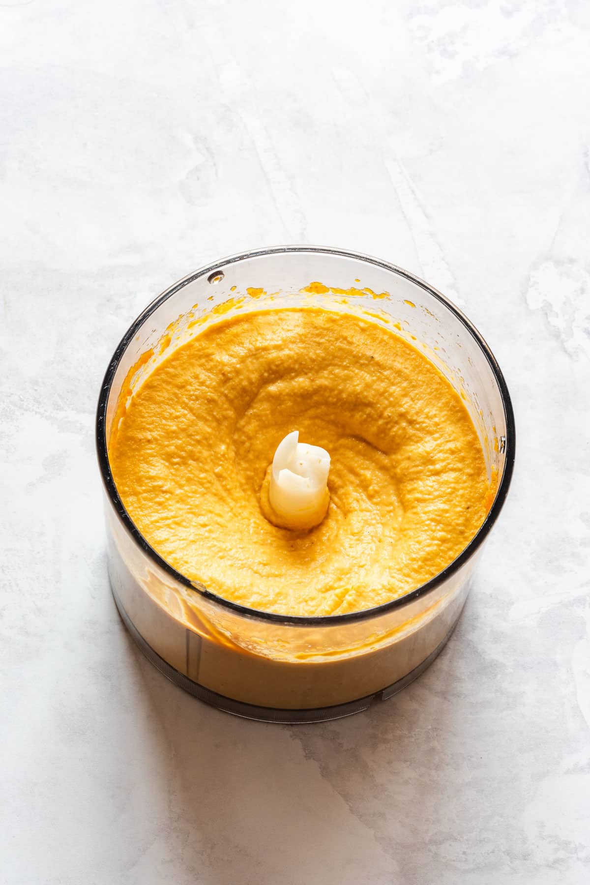 Smooth and creamy pumpkin hummus in a food processor bowl.