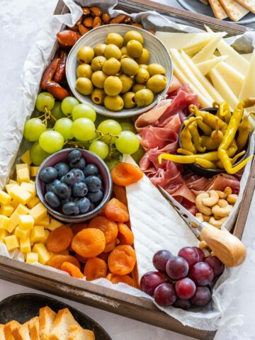 A beautifully arranged charcuterie board with variety of cheeses, cured meats and fruits.