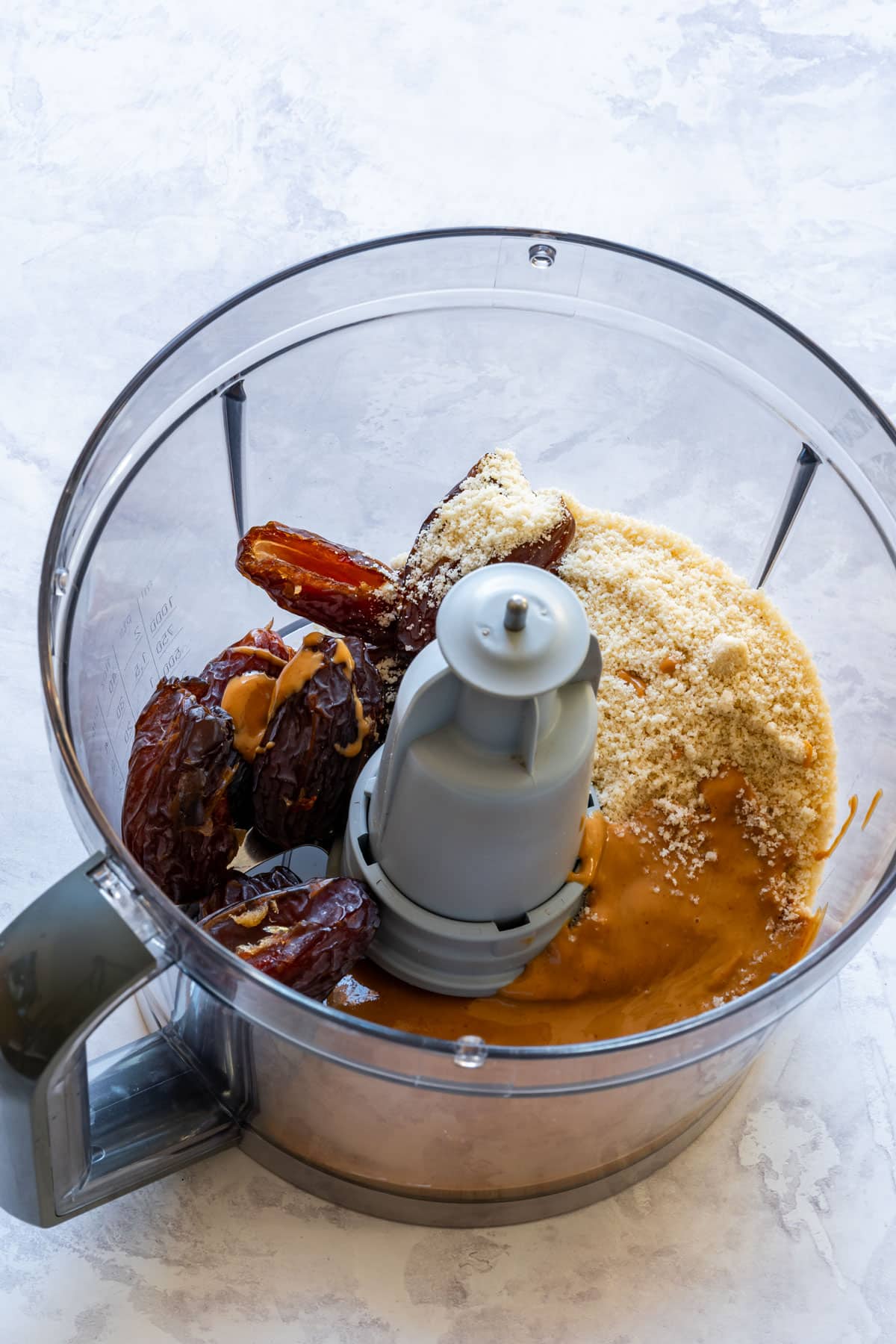 A food processor bowl with dates, almond flour, and peanut butter, ready to be blended.