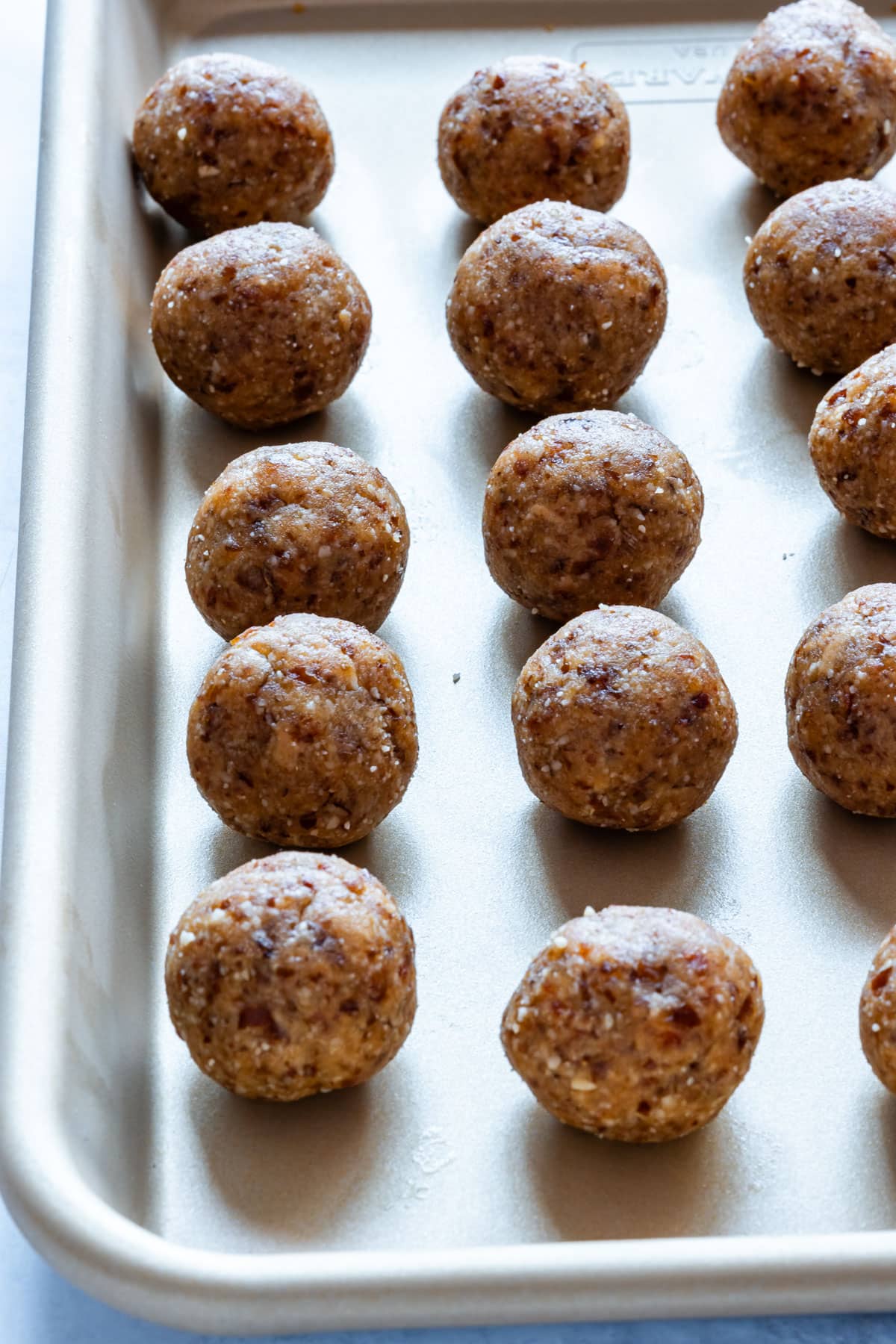 A baking tray with evenly spaced peanut butter balls, prepared for chocolate coating.