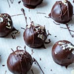 Luxurious chocolate truffles with drizzled chocolate and almond flakes on parchment paper.