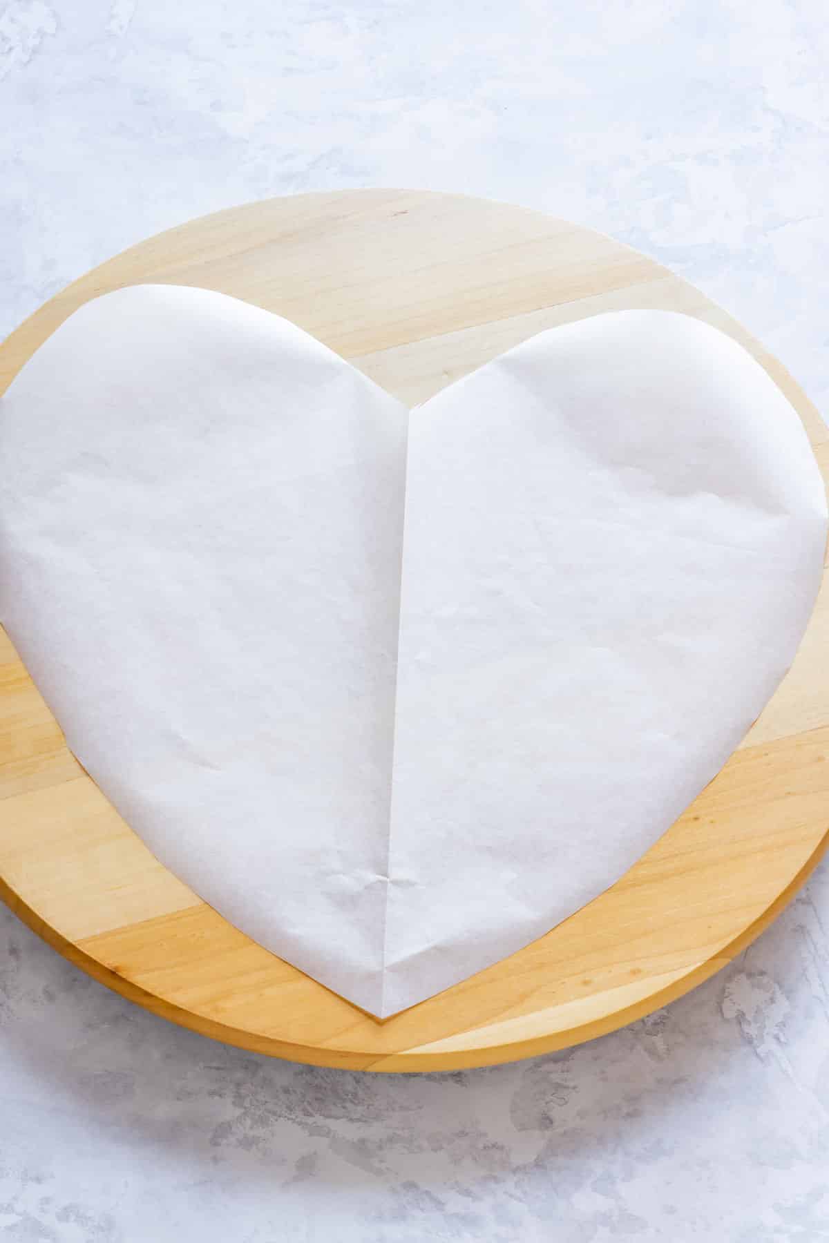 Heart cut out of parchment paper placed on a wooden surface.