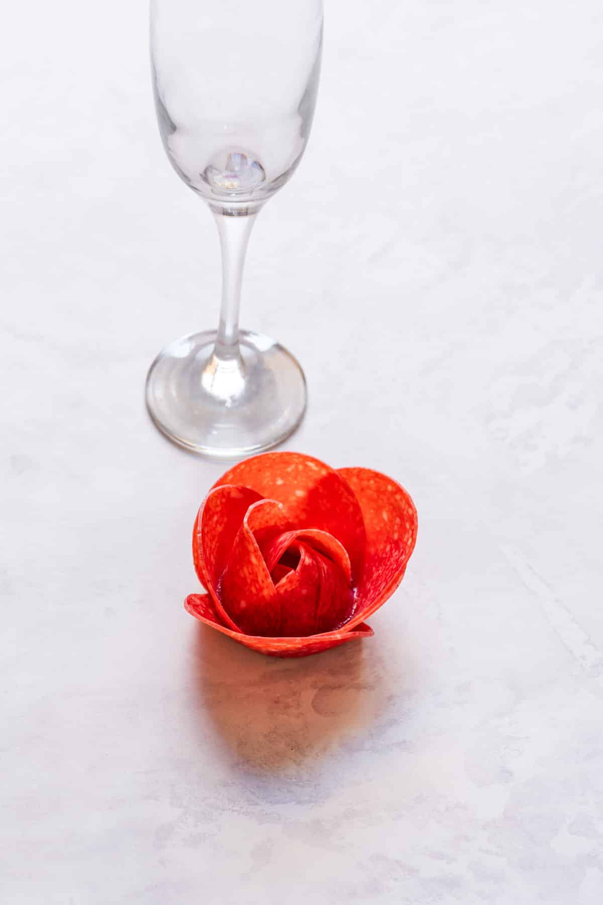 Salami rose next to the glass.