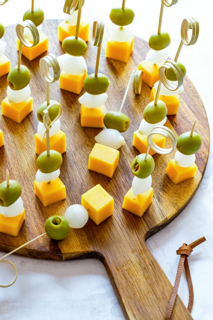 Close-up of Irish tricolor appetizer skewers with green olives, pearl onions and cheddar cheese arranged on a wooden serving board for a festive snack.